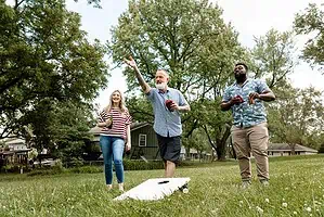 friends playing cornhole summer party park 1 opt 1
