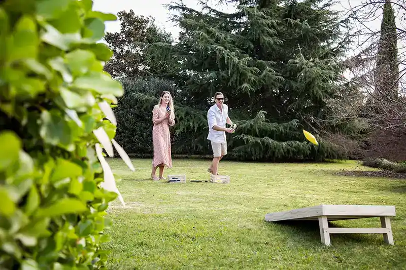 cornhole for beginners copy Couple playing a casual game of cornhole in their backyard with the best beginners gear